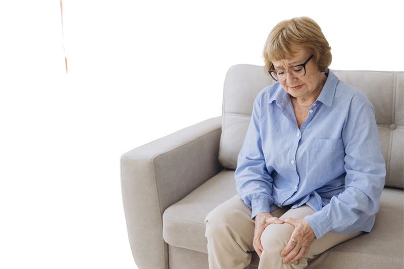 женщина сидит на диване и держится за колено