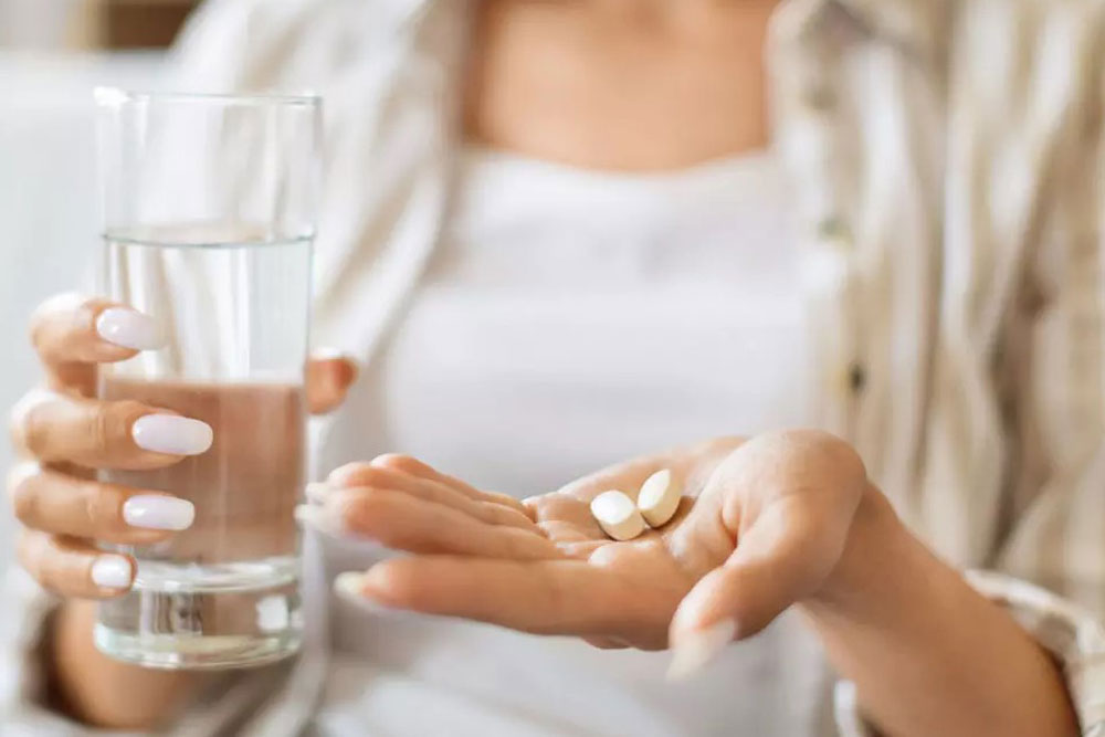 женщина держит таблетки и стакан с водой